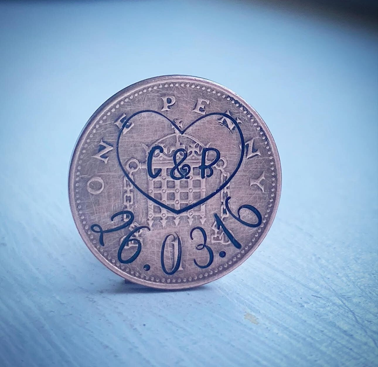 A personalized 1p coin gift with engraved initials and a date