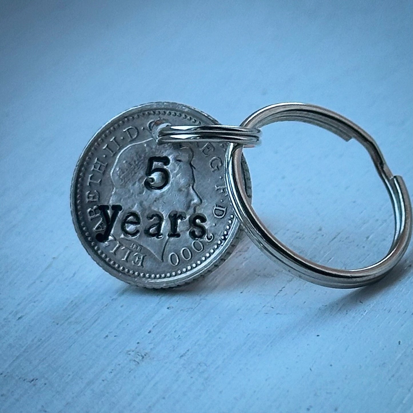 A silver-colored 5p coin keychain with '5 Years' stamped on the coin's surface, attached to a metallic keychain ring.