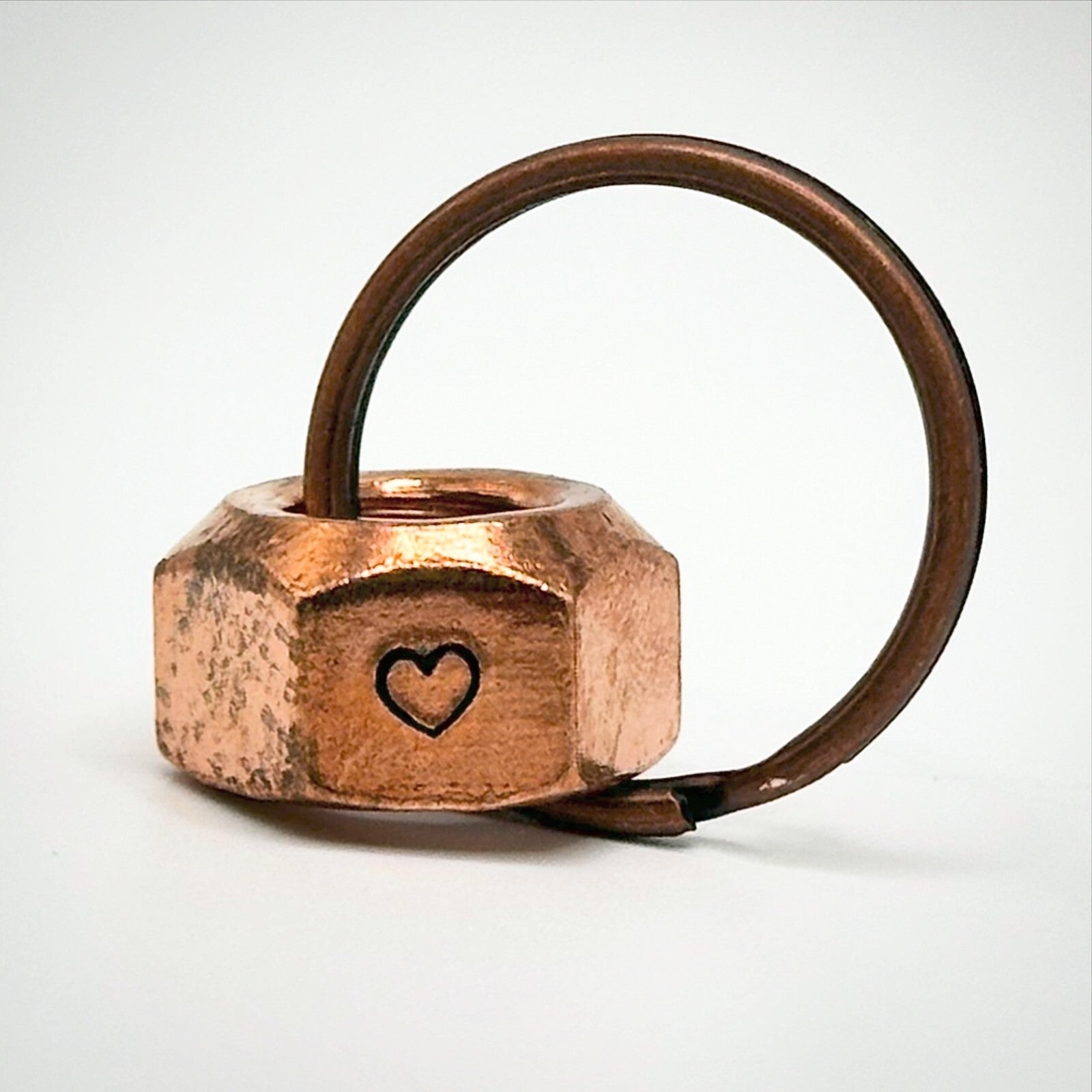A copper hex nut keyring with 'I STILL DO' stamped on the sides.