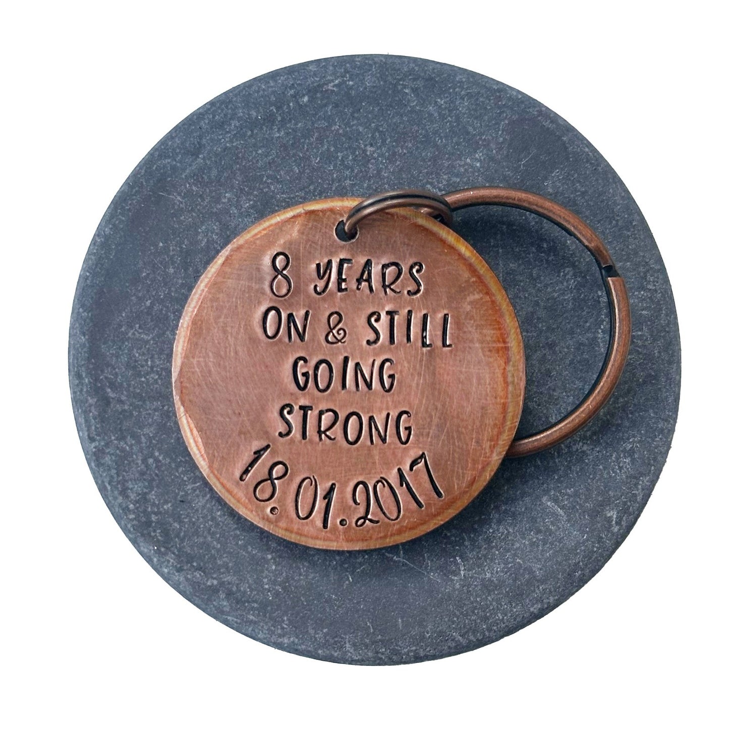 A bronze keychain with personalized engraving celebrating 8 years of marriage with date