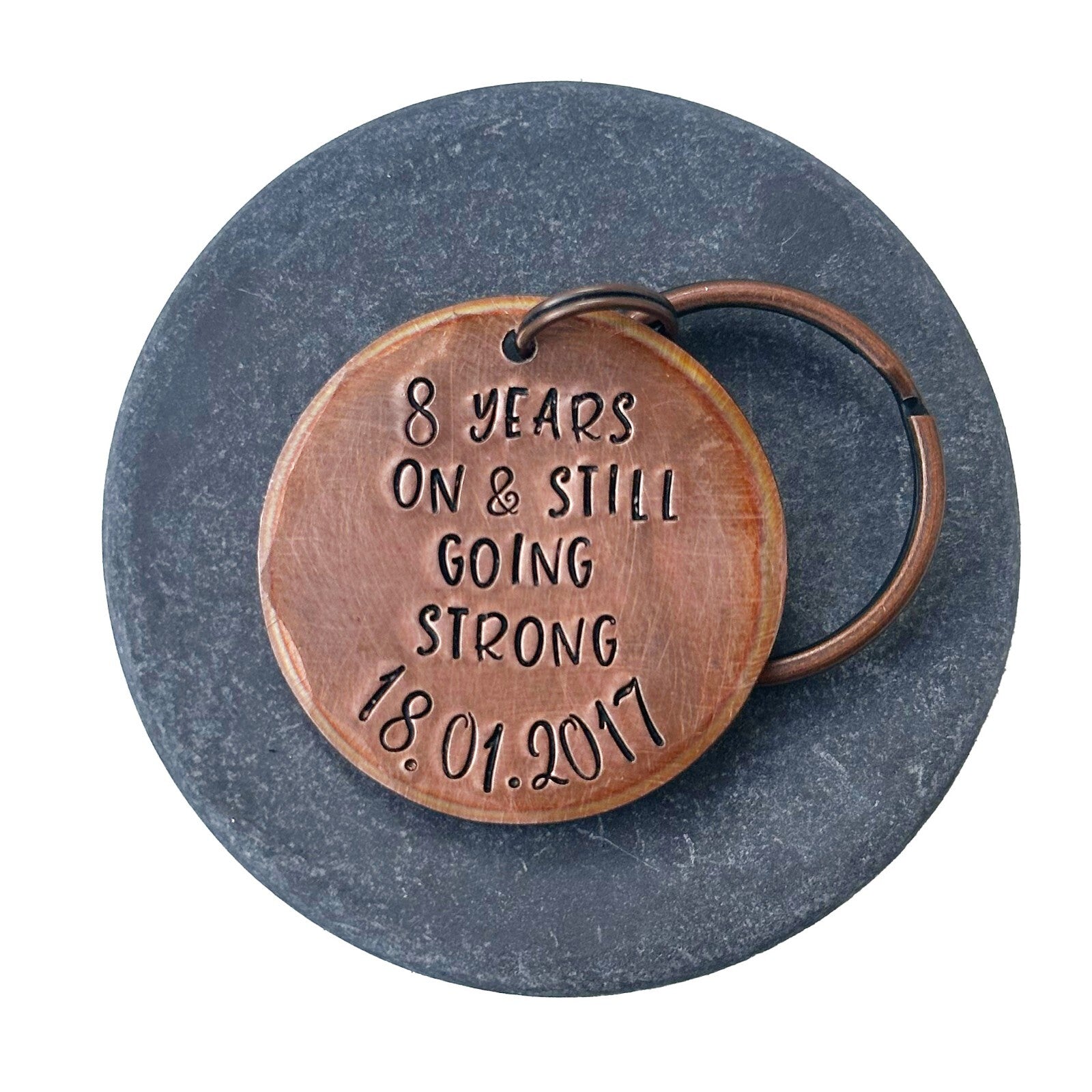 A bronze keychain with personalized engraving celebrating 8 years of marriage with date