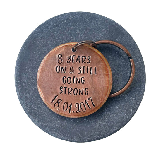 A bronze keychain with personalized engraving celebrating 8 years of marriage with date
