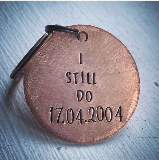 A copper keychain with the inscription 'I STILL DO 17.04.2004' stamped on it.