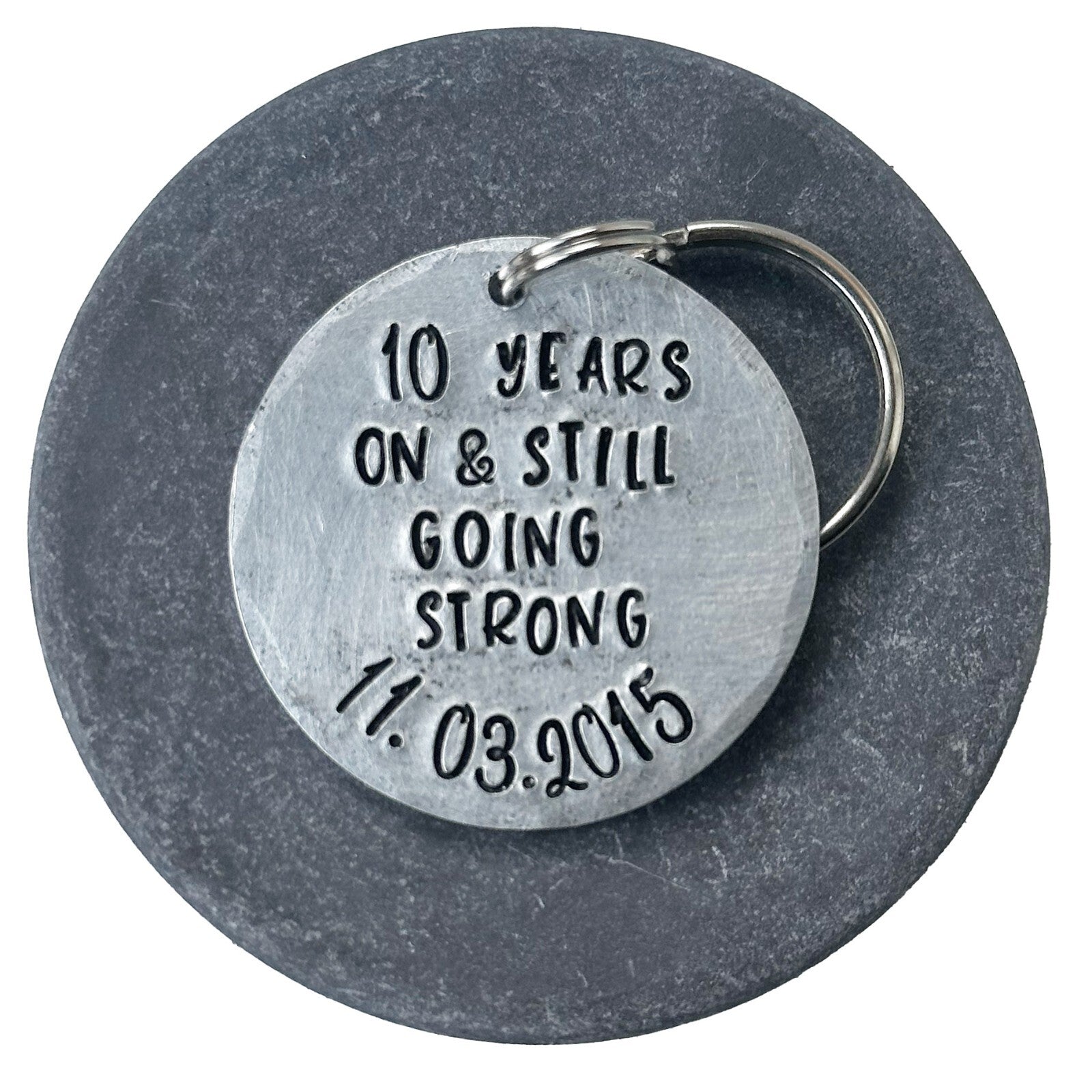 silver aluminum keychain with the inscription '10 years on & still going strong 11.03.2015'. anniversary gift