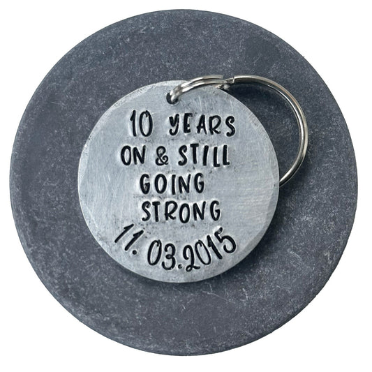 silver aluminum keychain with the inscription '10 years on & still going strong 11.03.2015'. anniversary gift