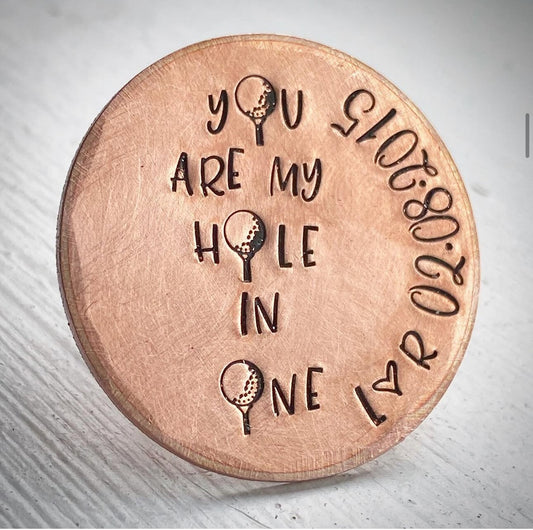 A bronze gift token with the inscription 'YOU ARE MY HOLE IN ONE' along with a golf ball design and a date