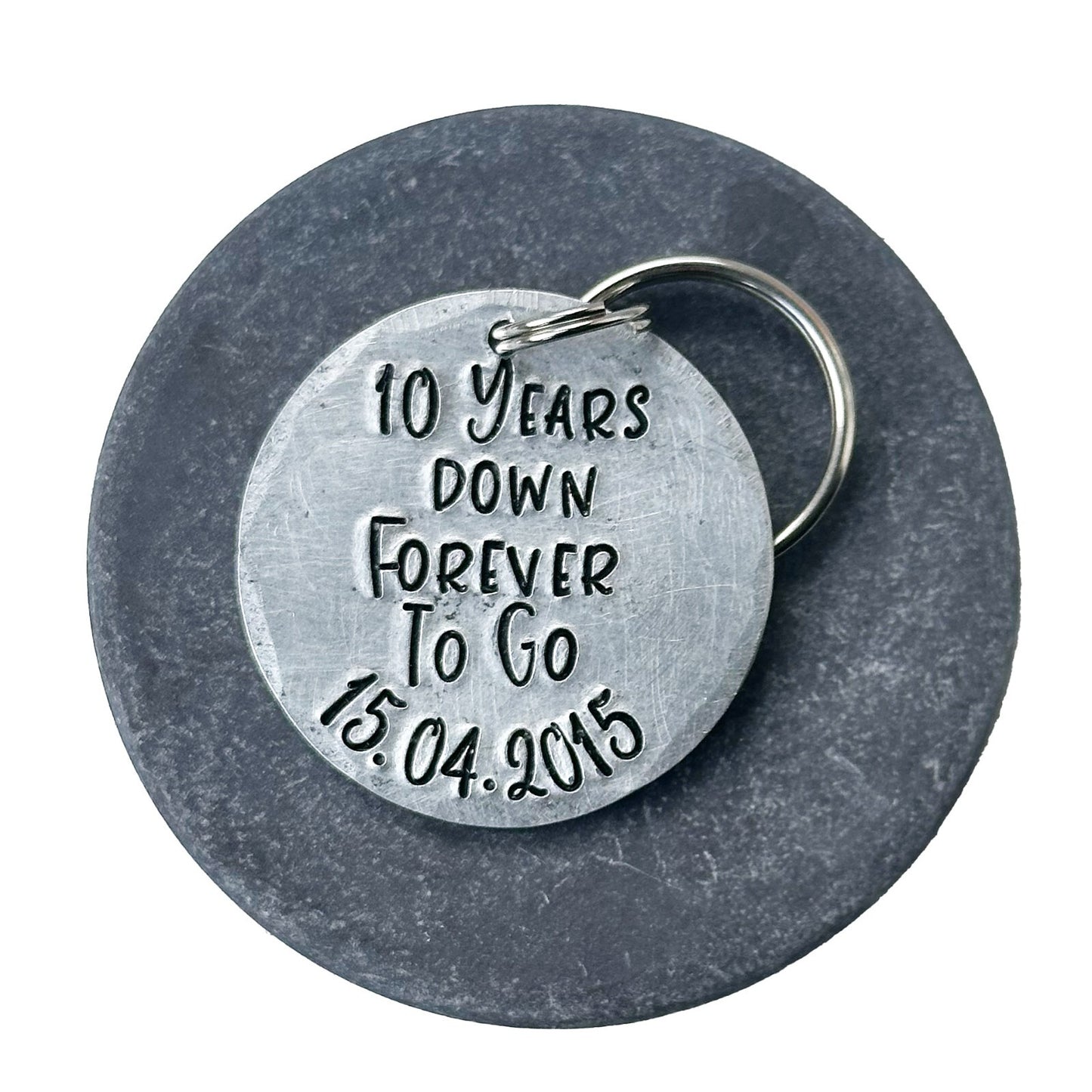 A silver aluminum keychain with the inscription '10 Years Down Forever To Go 15.04.2015'. anniversary gift