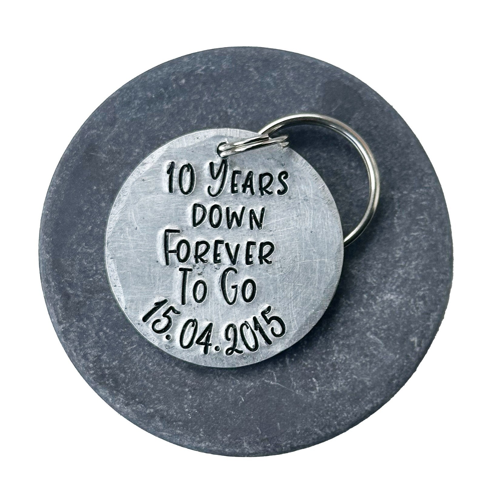 A silver aluminum keychain with the inscription '10 Years Down Forever To Go 15.04.2015'. anniversary gift