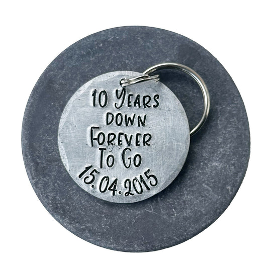 A silver aluminum keychain with the inscription '10 Years Down Forever To Go 15.04.2015'. anniversary gift