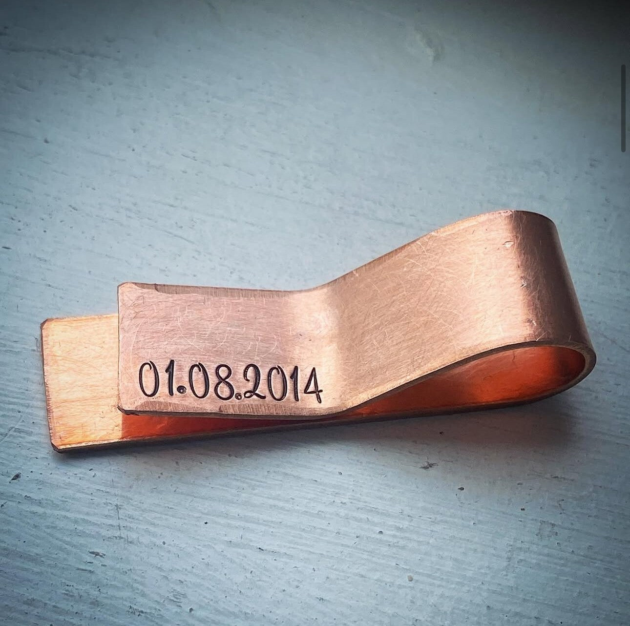 Copper clip with engraved date.