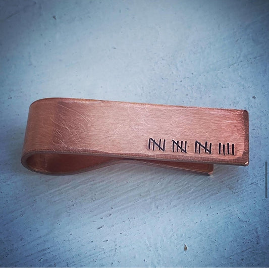 A bronze metal clip gift with engraved markings.